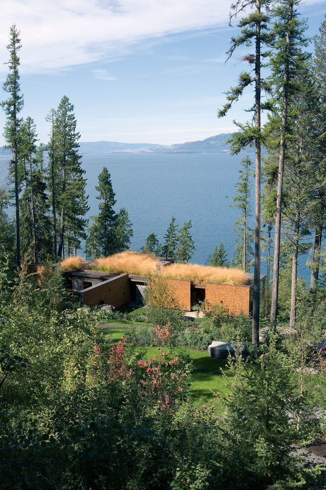 Идея дизайна: одноэтажный, деревянный дом в стиле рустика с плоской крышей и зеленой крышей для охотников