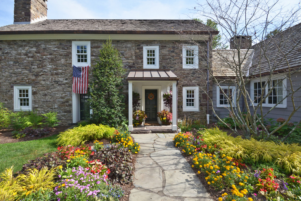 Example of a large cottage gray two-story stone exterior home design in New York with a mixed material roof