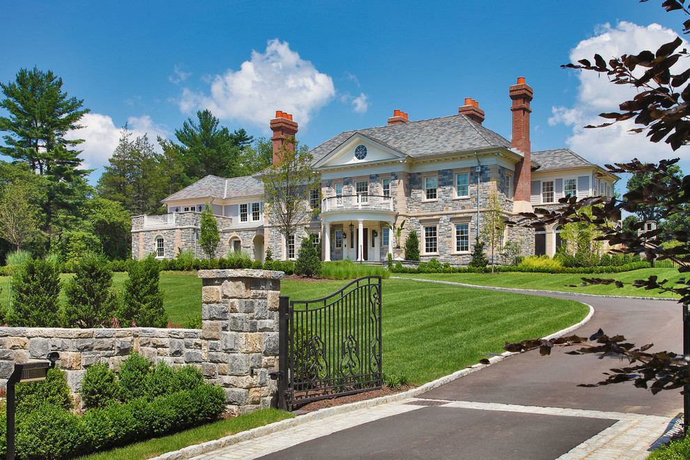 Example of a classic two-story stone exterior home design in New York