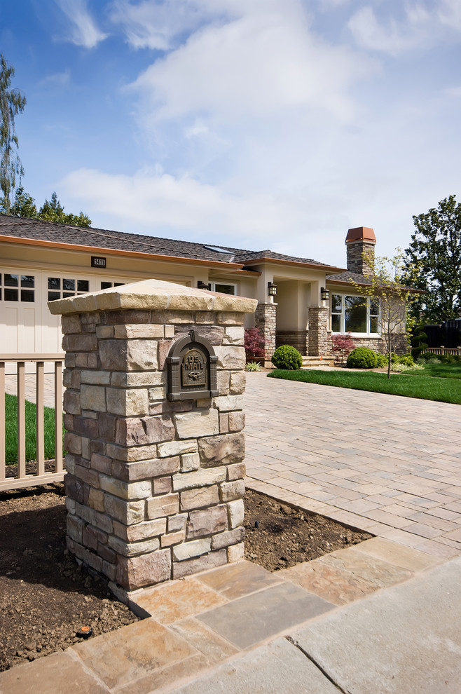 Diseño de fachada de casa beige de estilo americano grande de una planta con revestimiento de estuco, tejado a dos aguas y tejado de teja de madera