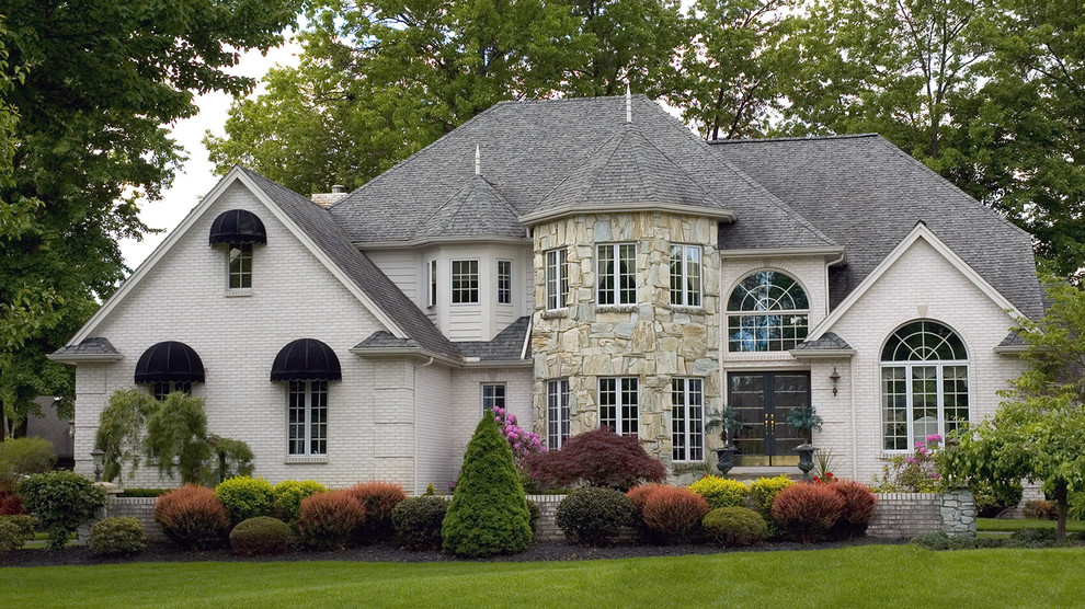 Example of a mid-sized classic white two-story brick exterior home design with a shingle roof