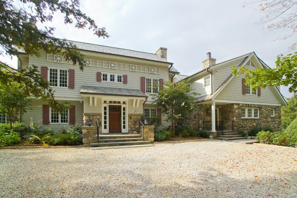 Cette image montre une façade de maison beige traditionnelle à deux étages et plus avec un revêtement mixte.