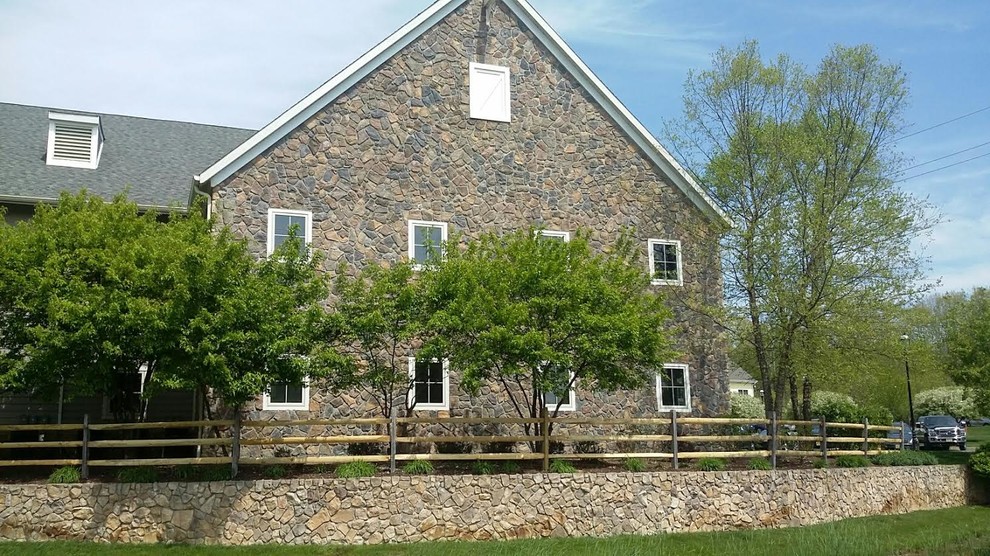 На фото: большой, двухэтажный, серый частный загородный дом в классическом стиле с облицовкой из камня, двускатной крышей и крышей из гибкой черепицы