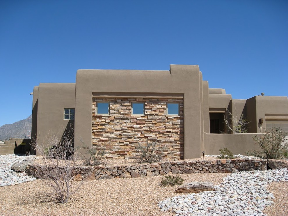 Cette photo montre une façade de maison marron sud-ouest américain en pierre de plain-pied avec un toit plat.