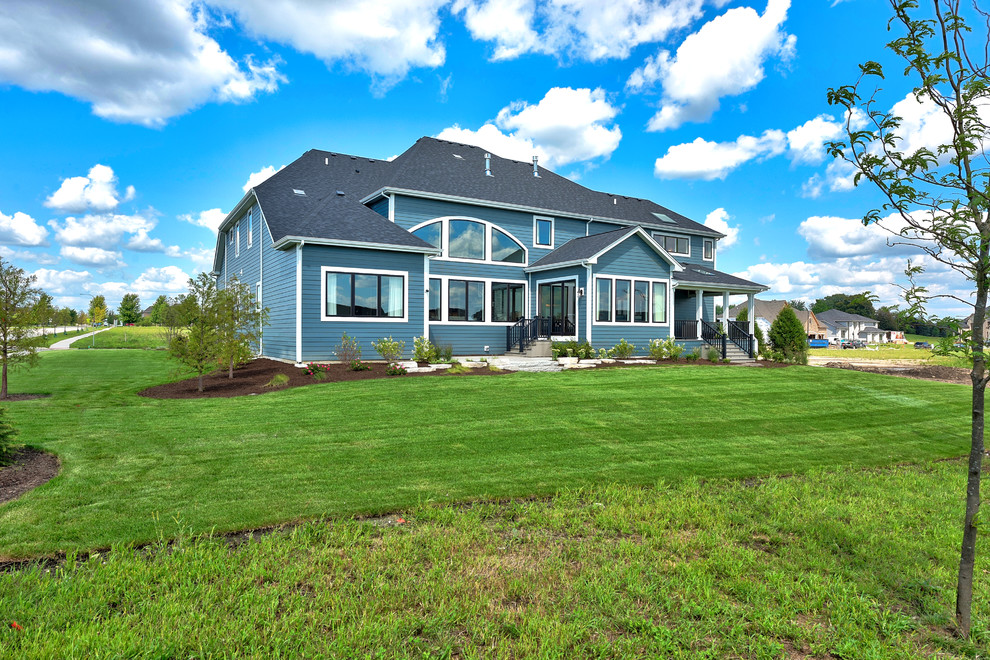Imagen de fachada de casa azul costera grande de tres plantas con revestimiento de aglomerado de cemento y tejado de teja de madera