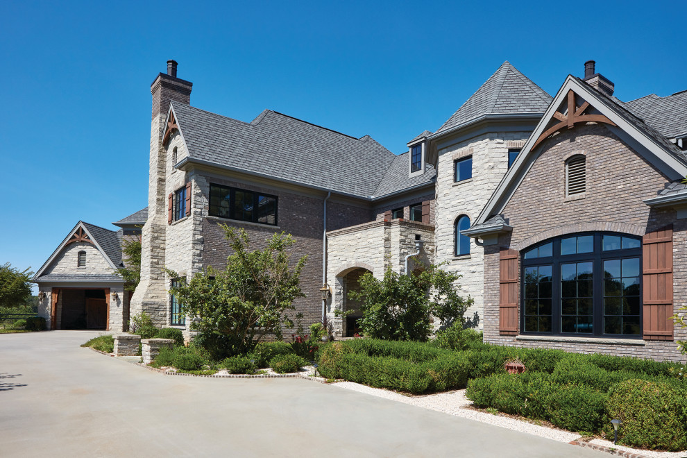 Huge traditional gray three-story stone house exterior idea in Other with a shingle roof and a hip roof