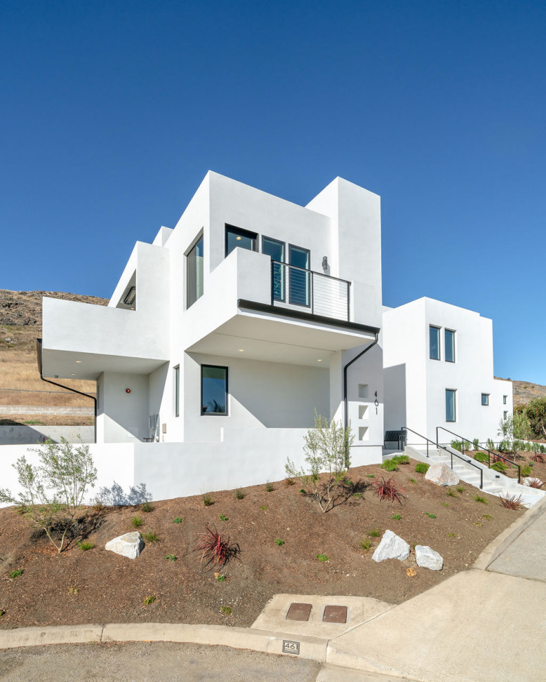 На фото: двухэтажный, белый частный загородный дом среднего размера в стиле модернизм с облицовкой из цементной штукатурки и плоской крышей
