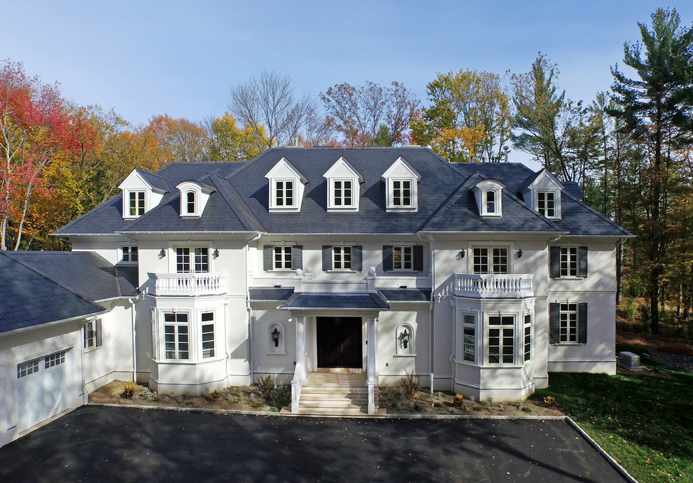 Ejemplo de fachada de casa blanca clásica extra grande de tres plantas con revestimiento de estuco, tejado a cuatro aguas y tejado de teja de madera