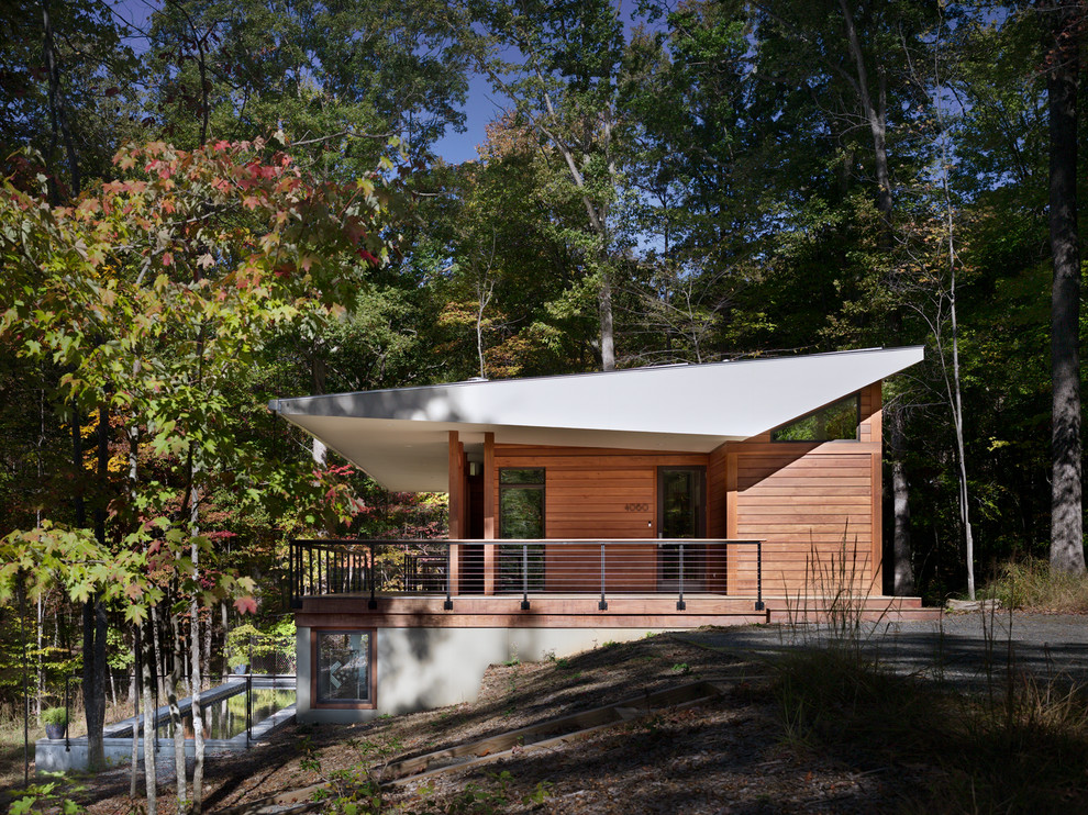 На фото: деревянный, маленький, двухэтажный, коричневый дом в современном стиле с односкатной крышей для на участке и в саду