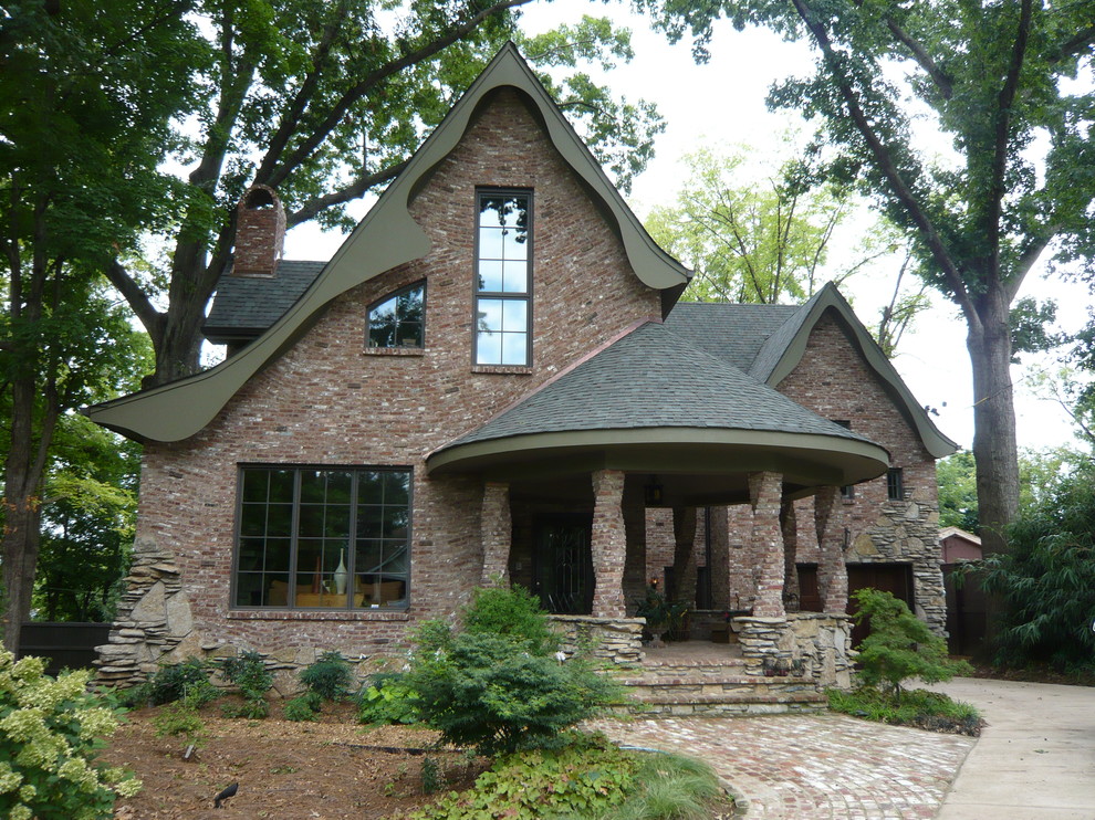 This is an example of a medium sized and red eclectic two floor brick house exterior in Nashville.