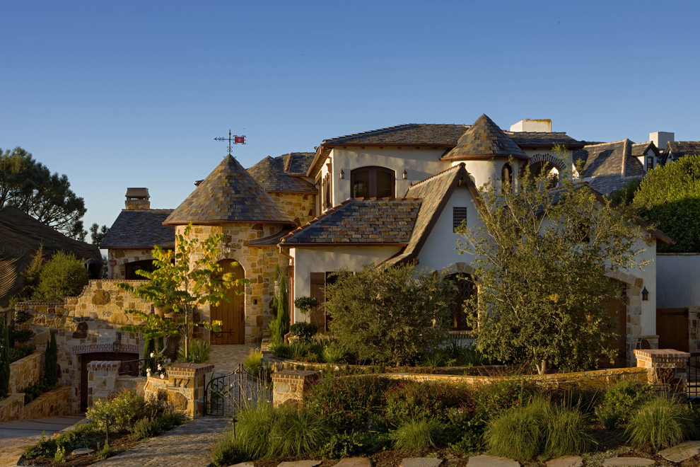 Large traditional white two-story stone exterior home idea in Orange County
