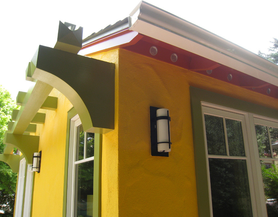 Imagen de fachada de casa amarilla mediterránea de tamaño medio de una planta con revestimiento de estuco, tejado a dos aguas y tejado de teja de madera