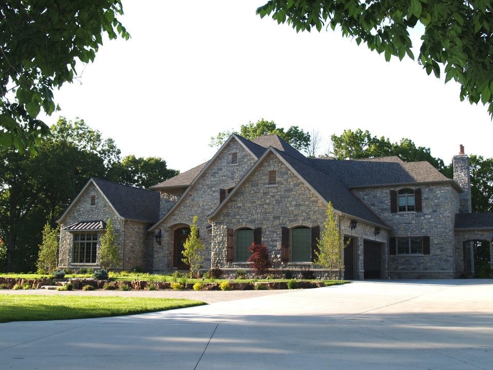 Cette image montre une grande façade de maison multicolore traditionnelle en pierre à un étage avec un toit mixte.