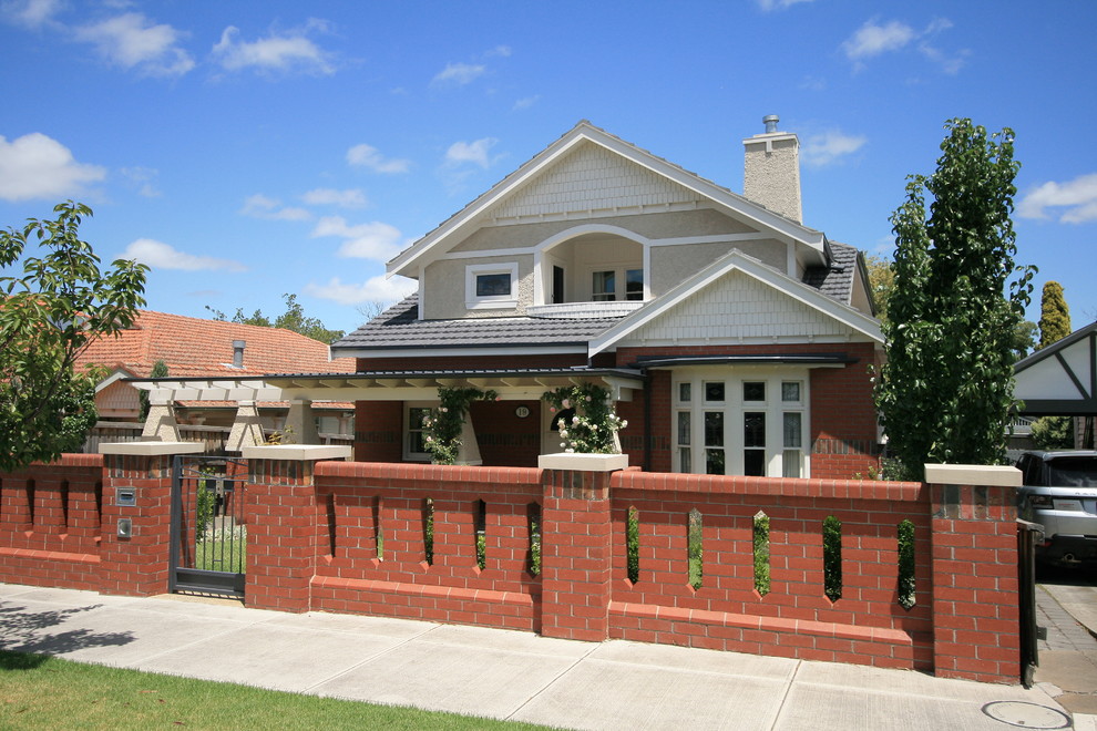 Esempio della villa american style a tre piani con rivestimento in mattoni, tetto a capanna e copertura in tegole