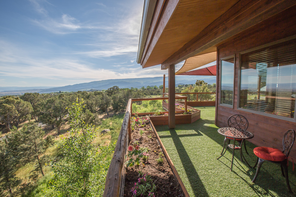 Imagen de fachada de casa marrón, rústica, grande, de tres plantas, con revestimiento de madera, tejado de un solo tendido y tejado de teja de madera