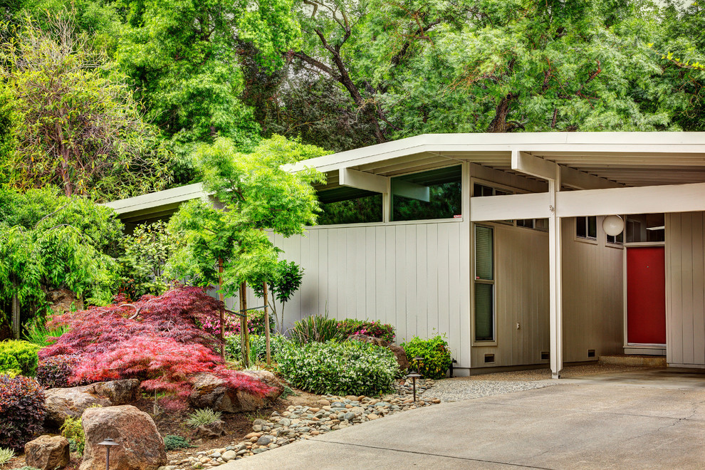 Beige midcentury bungalow house exterior in Sacramento with wood cladding and a pitched roof.