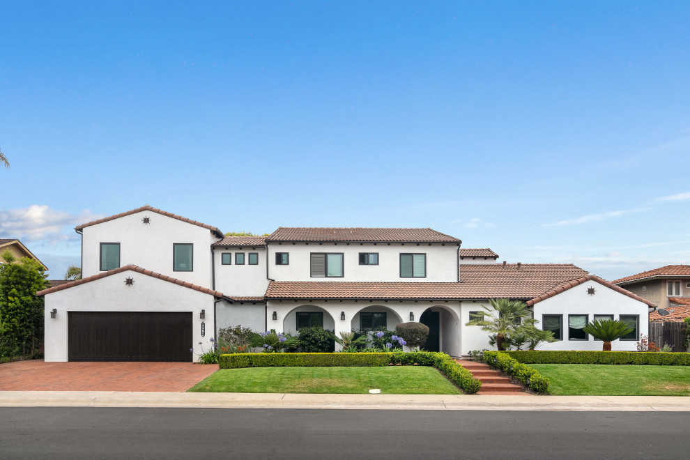 Zweistöckiges Mediterranes Einfamilienhaus mit weißer Fassadenfarbe, Satteldach, Ziegeldach und braunem Dach in San Diego