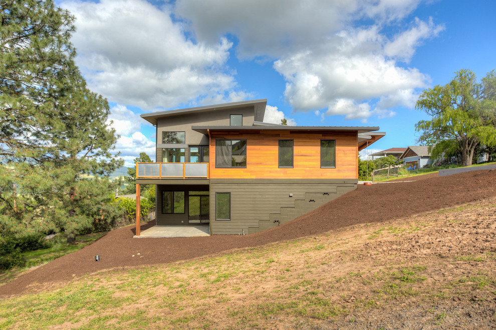 На фото: большой, двухэтажный, разноцветный частный загородный дом в стиле модернизм с комбинированной облицовкой, односкатной крышей и металлической крышей с