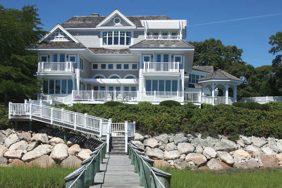 Idée de décoration pour une grande façade de maison grise marine en bois à deux étages et plus avec un toit à quatre pans.