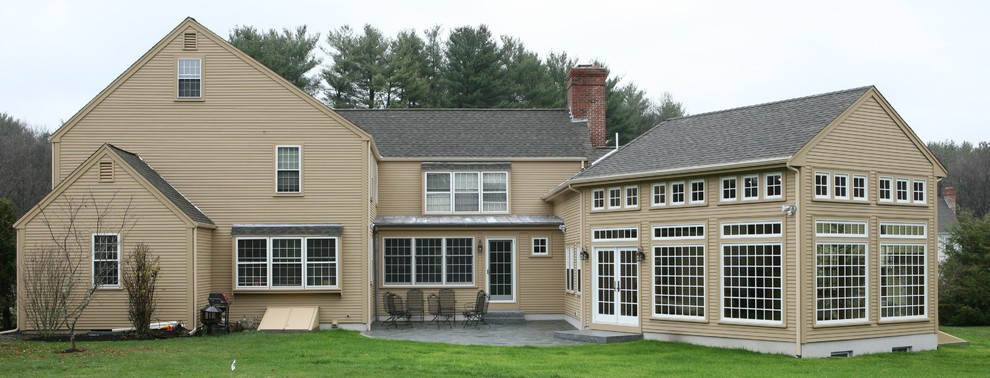 Immagine della villa grande beige classica a due piani con tetto a capanna e copertura a scandole