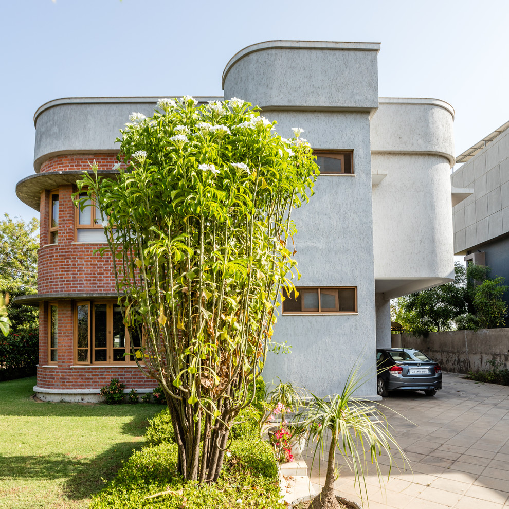 Inspiration for a gey contemporary two floor detached house in Ahmedabad with mixed cladding and a flat roof.