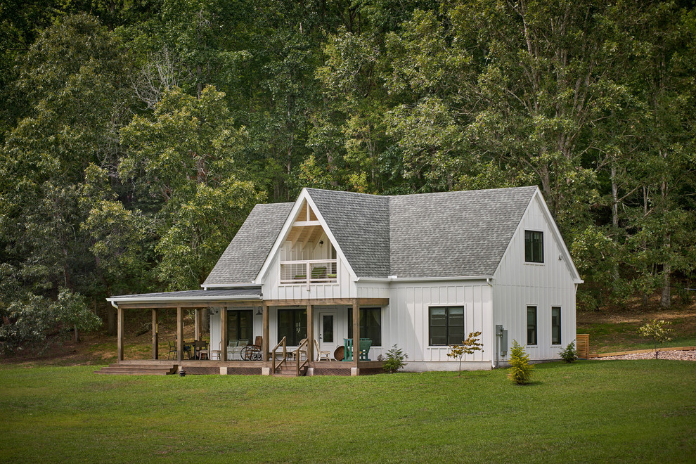 Esempio della villa piccola bianca country a due piani con tetto a capanna e copertura a scandole
