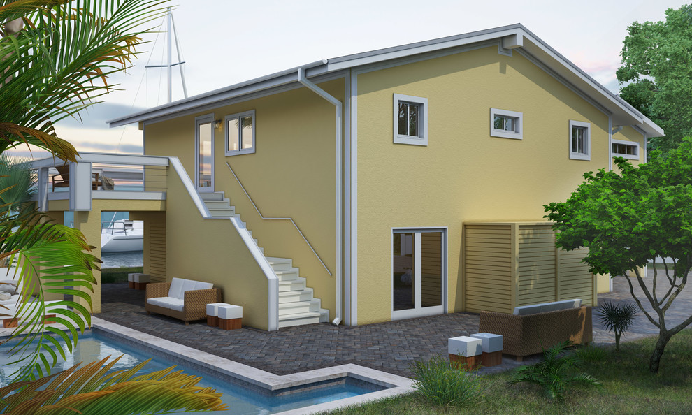 Cette image montre une grande façade de maison jaune design en stuc à un étage avec un toit à deux pans et un toit en métal.