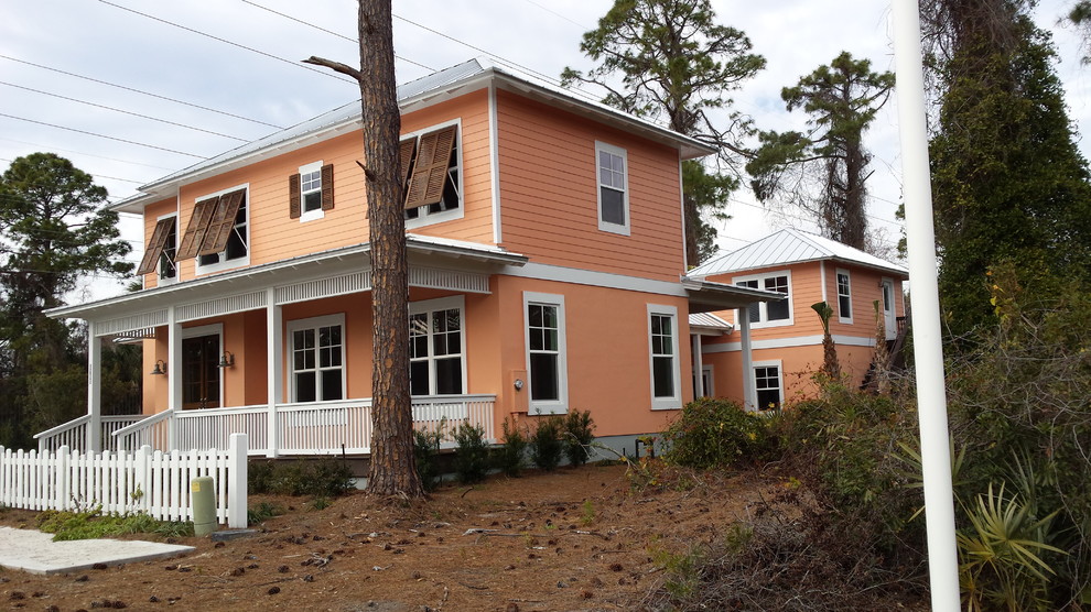 Idée de décoration pour une façade de maison orange marine de taille moyenne et à un étage avec un revêtement mixte et un toit à croupette.