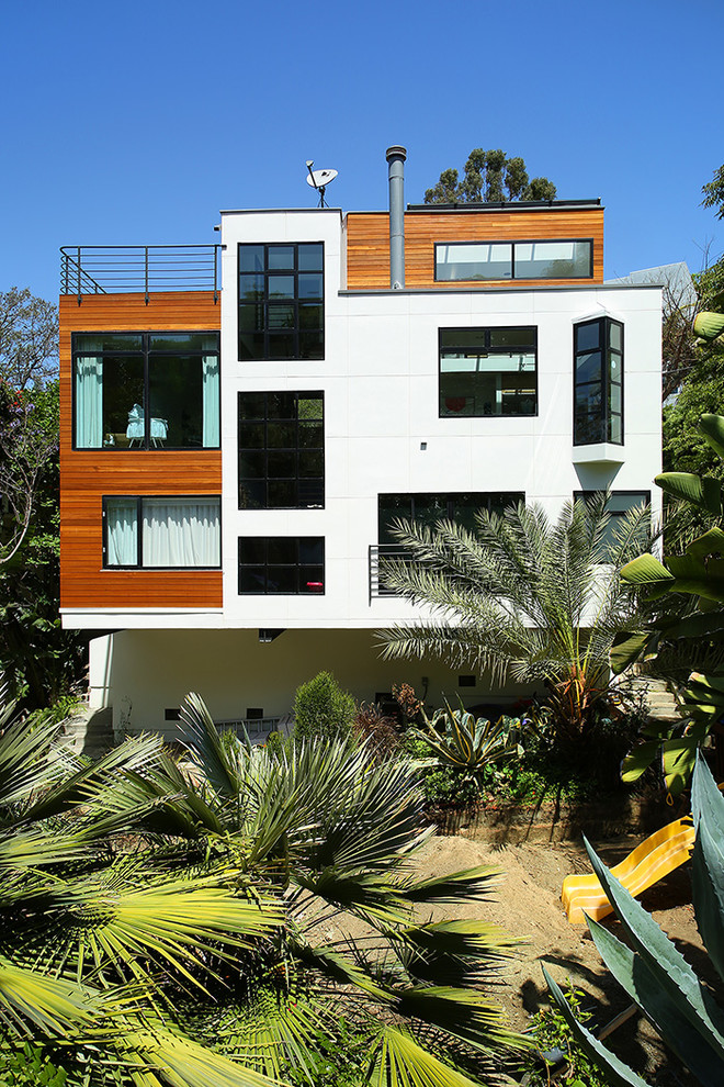 Diseño de fachada de casa blanca actual de tamaño medio de tres plantas con revestimiento de madera y tejado plano