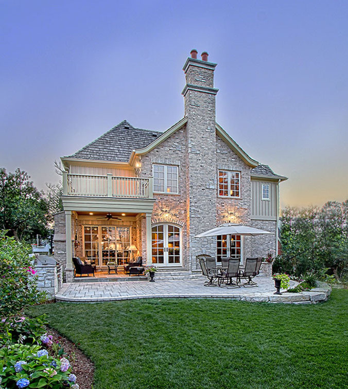 Пример оригинального дизайна: большой, двухэтажный, бежевый дом в классическом стиле с облицовкой из камня и полувальмовой крышей