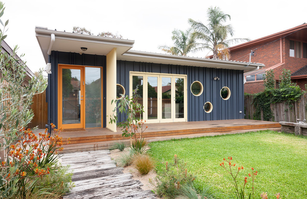 На фото: одноэтажный, деревянный, синий частный загородный дом среднего размера в современном стиле с плоской крышей и металлической крышей с