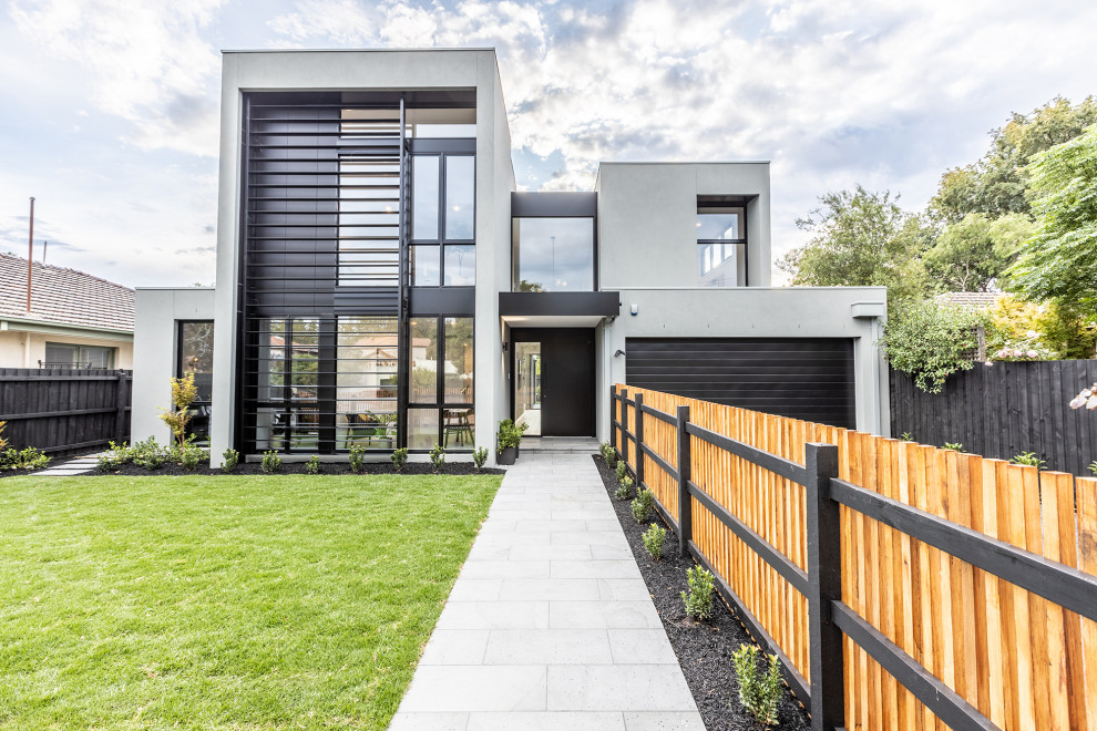 Large trendy gray two-story stucco exterior home photo in Melbourne with a metal roof and a black roof