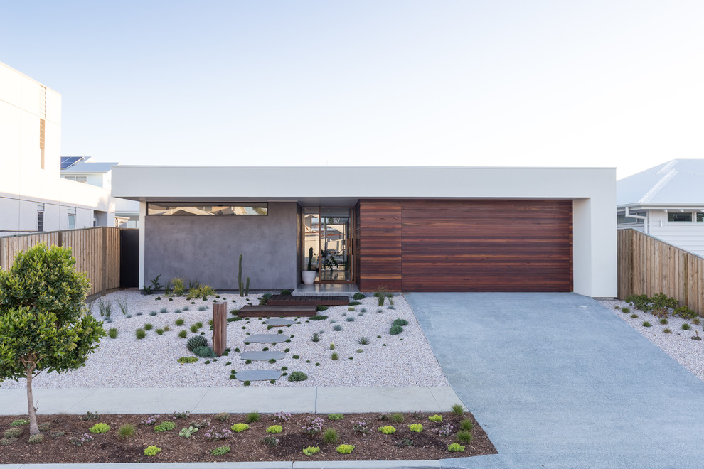 Cette image montre une façade de maison blanche design de plain-pied avec un revêtement mixte et un toit en appentis.