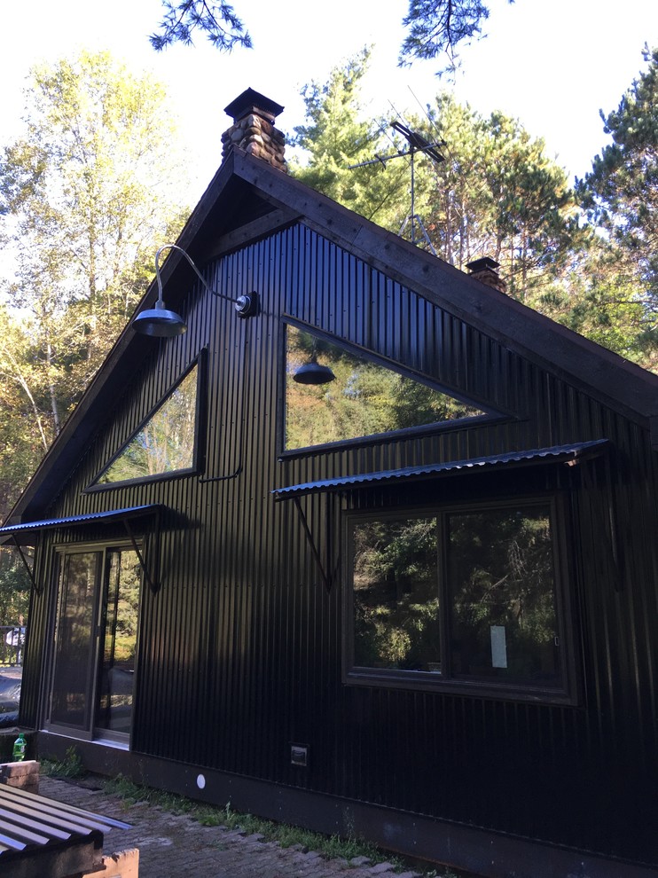 Ispirazione per la facciata di una casa nera eclettica con rivestimento in metallo e tetto a capanna