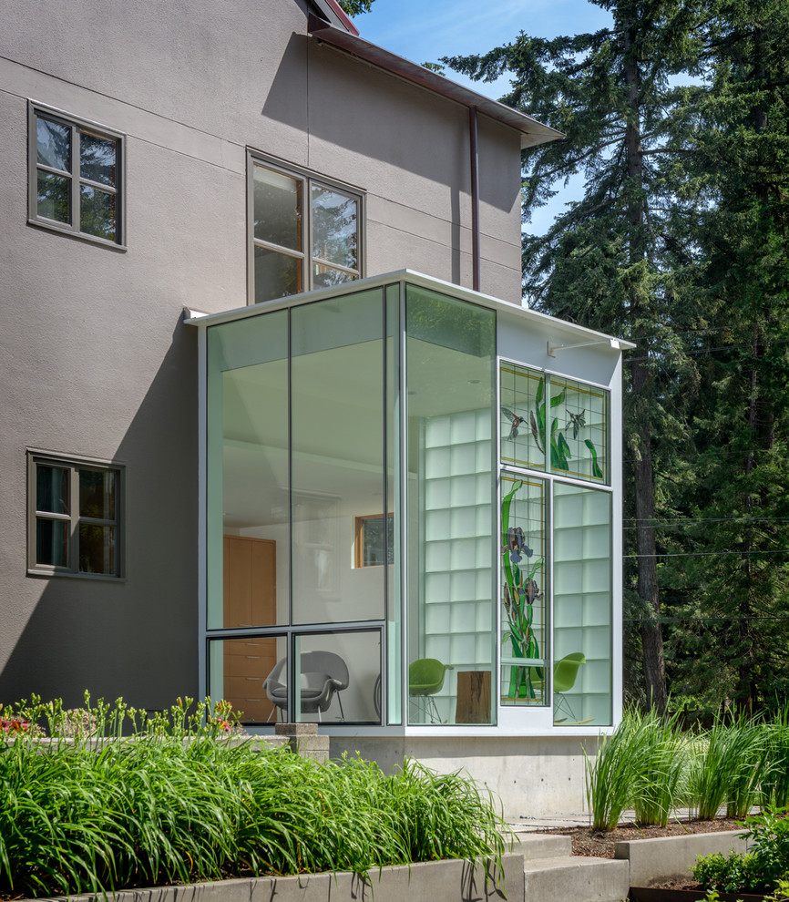 Large minimalist gray three-story stucco house exterior photo in Portland with a hip roof and a metal roof