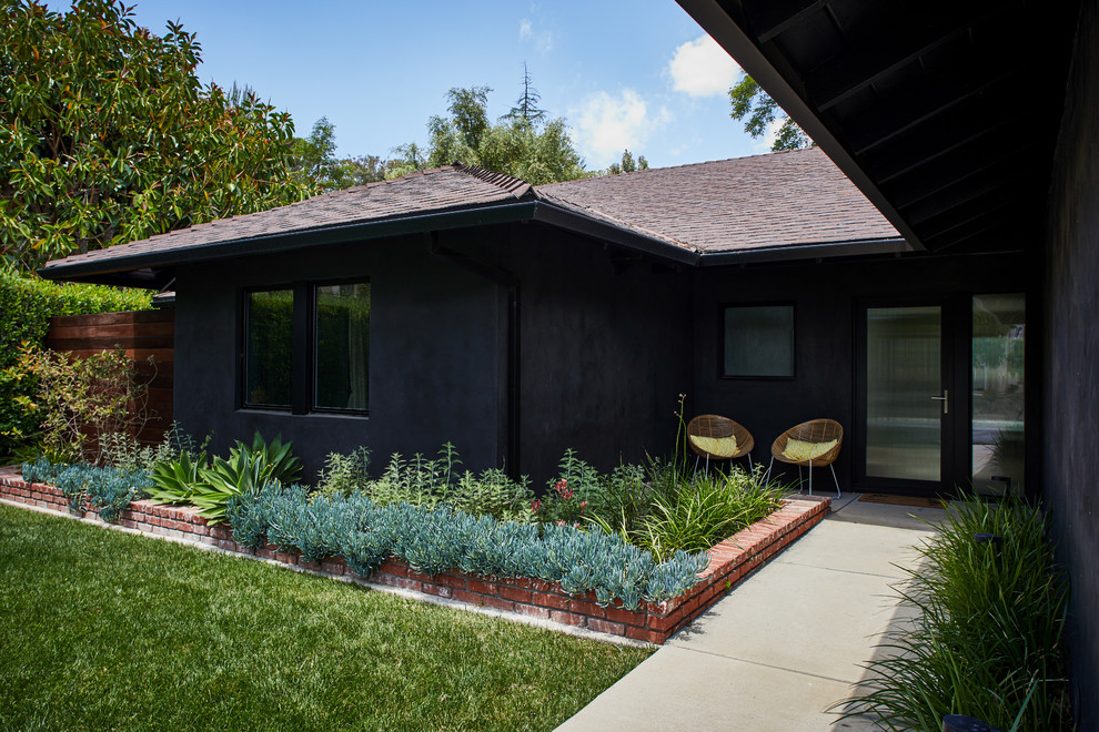 Example of a mid-sized danish black one-story stucco house exterior design in Los Angeles with a hip roof and a shingle roof