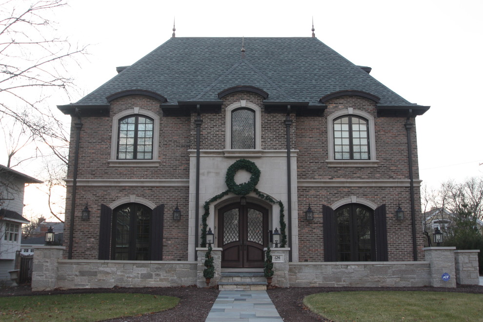Cette image montre une façade de maison marron traditionnelle en brique à deux étages et plus avec un toit à quatre pans.