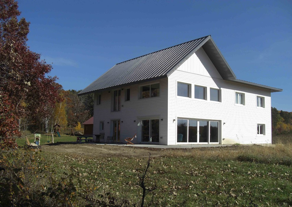 Exemple d'une façade de maison métallique et verte tendance de taille moyenne et à deux étages et plus avec un toit à deux pans et un toit en métal.