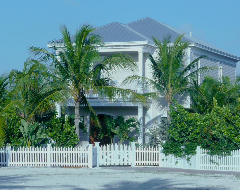Diseño de fachada beige tropical de tamaño medio de dos plantas con revestimiento de aglomerado de cemento y tejado a cuatro aguas