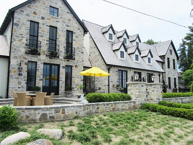 Photo of a large and gey traditional two floor house exterior in Toronto with stone cladding and a pitched roof.