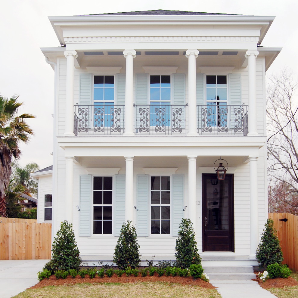 Esempio della facciata di una casa bianca classica a due piani con rivestimento in legno e tetto a padiglione