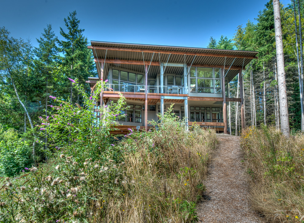 Photo of a rustic two floor glass house exterior in Seattle with a flat roof.