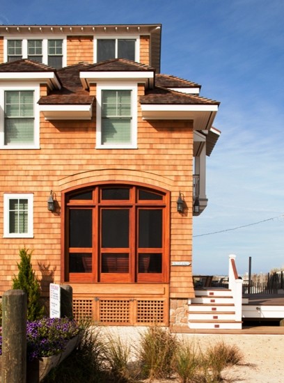 Foto della villa grande marrone stile marinaro a tre piani con rivestimento in legno, tetto a padiglione e copertura a scandole