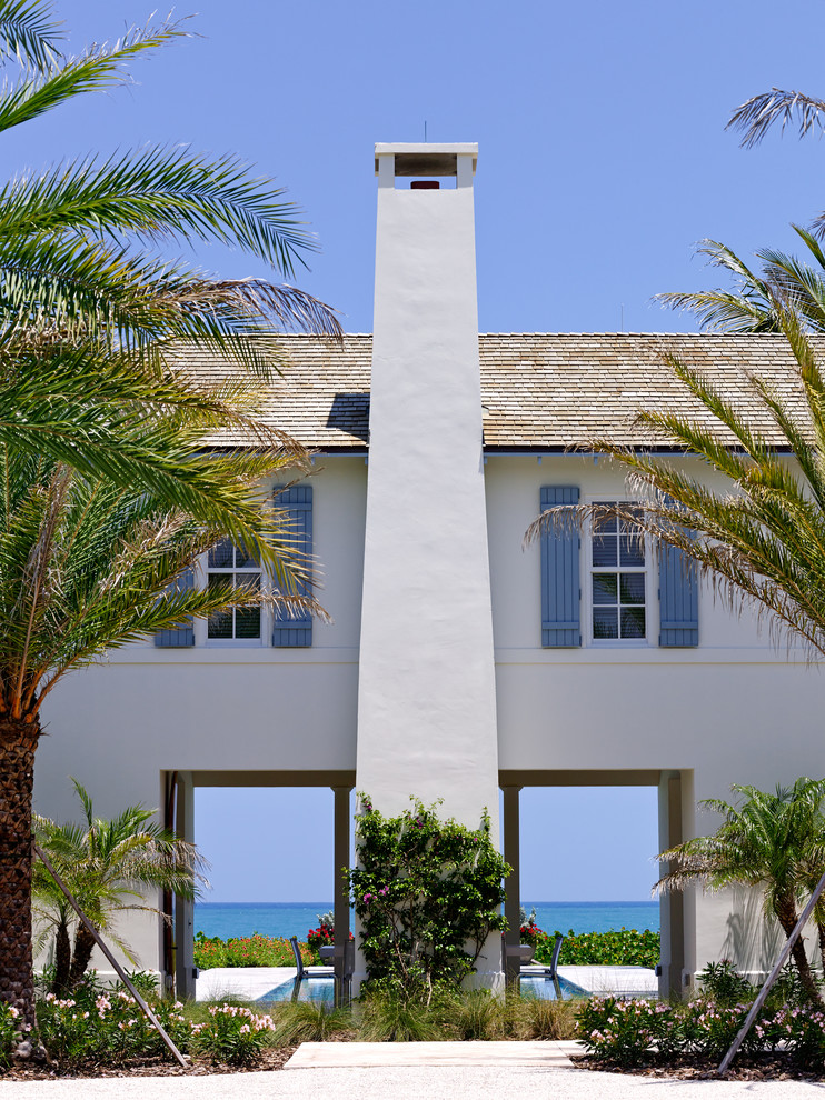 Inspiration for a large timeless white two-story stucco exterior home remodel in Miami with a hip roof
