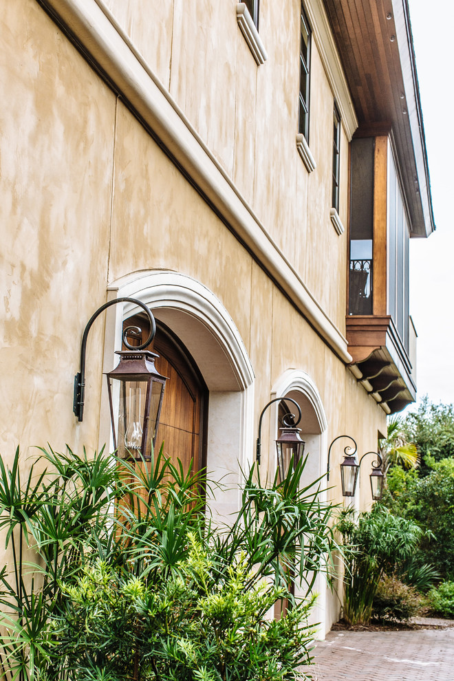 Esempio della villa grande beige mediterranea a due piani con rivestimento in stucco