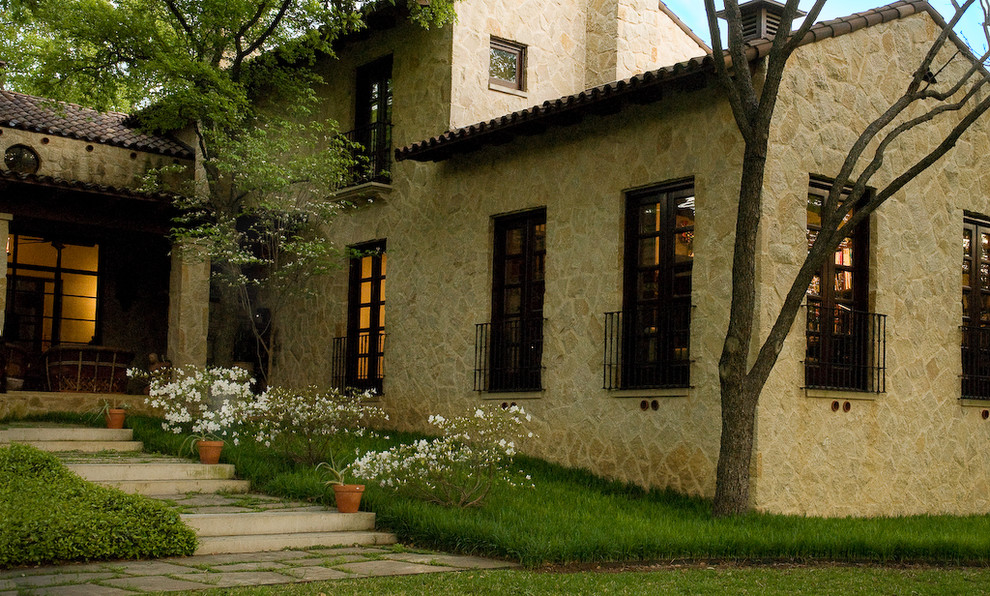 Inspiration for a large mediterranean brown two-story stone exterior home remodel in Dallas with a tile roof