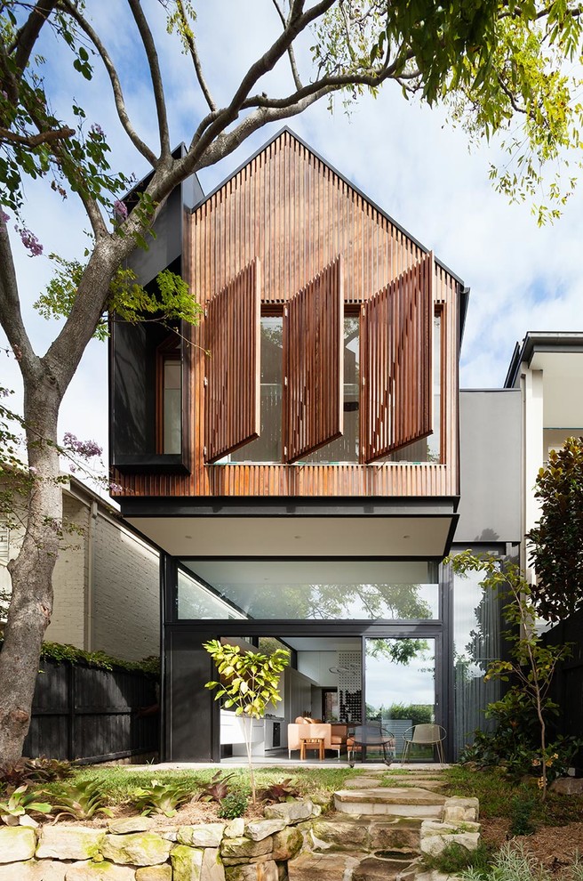 Inspiration for a medium sized and black modern two floor house exterior in Sydney with wood cladding and a pitched roof.