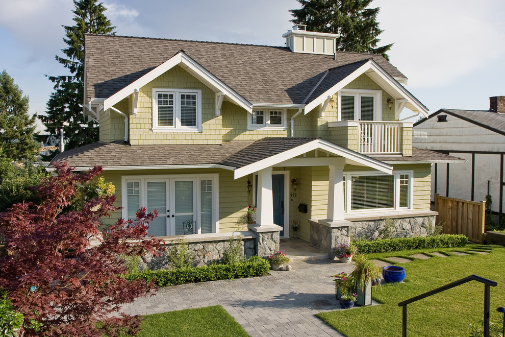 Example of a large arts and crafts yellow two-story wood exterior home design in Vancouver with a shingle roof