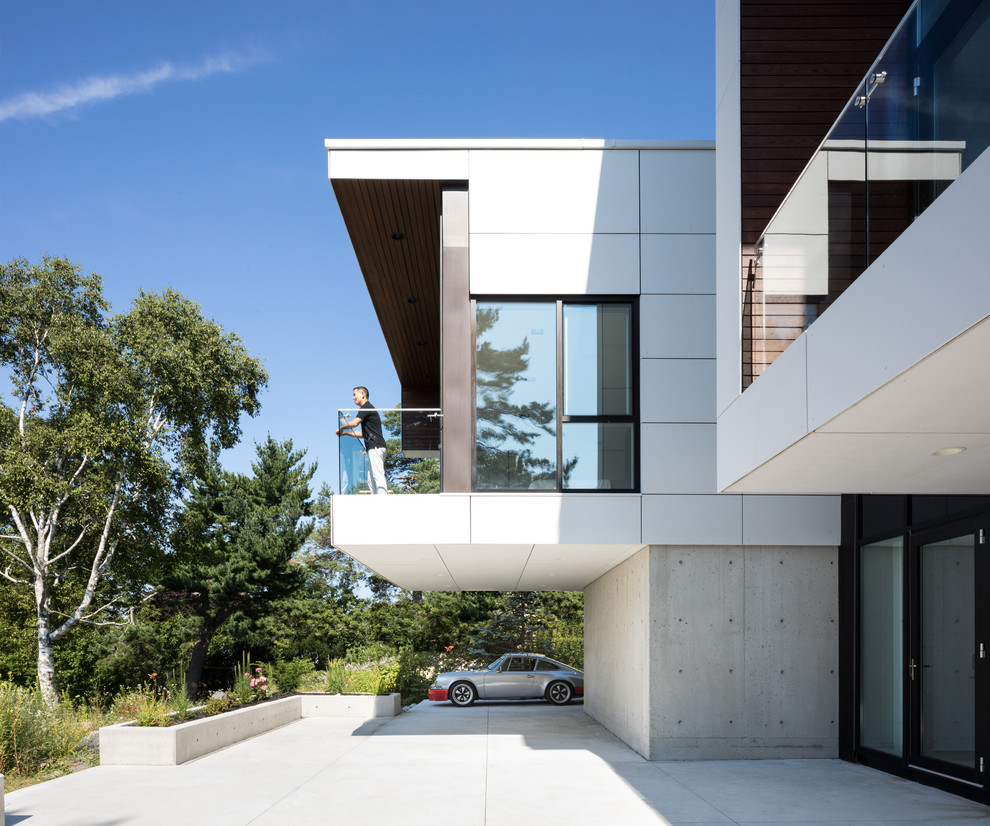 Imagen de fachada de casa blanca moderna a niveles con revestimiento de aglomerado de cemento y tejado plano