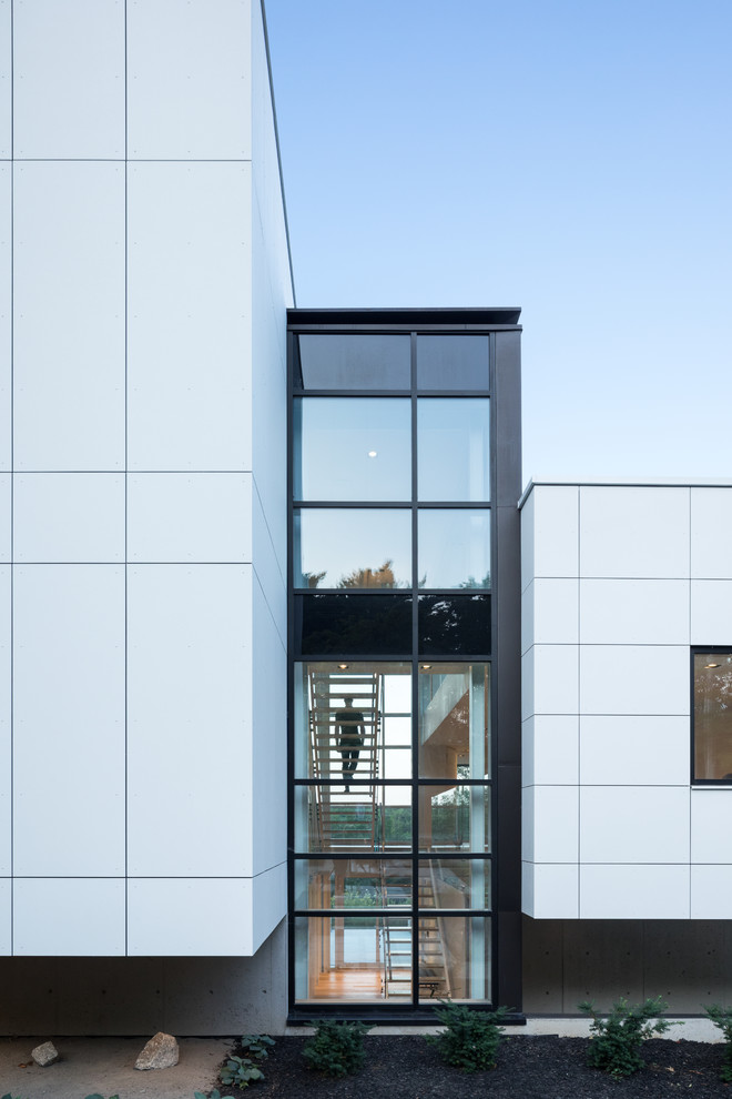 Cette photo montre une façade de maison blanche moderne en panneau de béton fibré à niveaux décalés avec un toit plat.